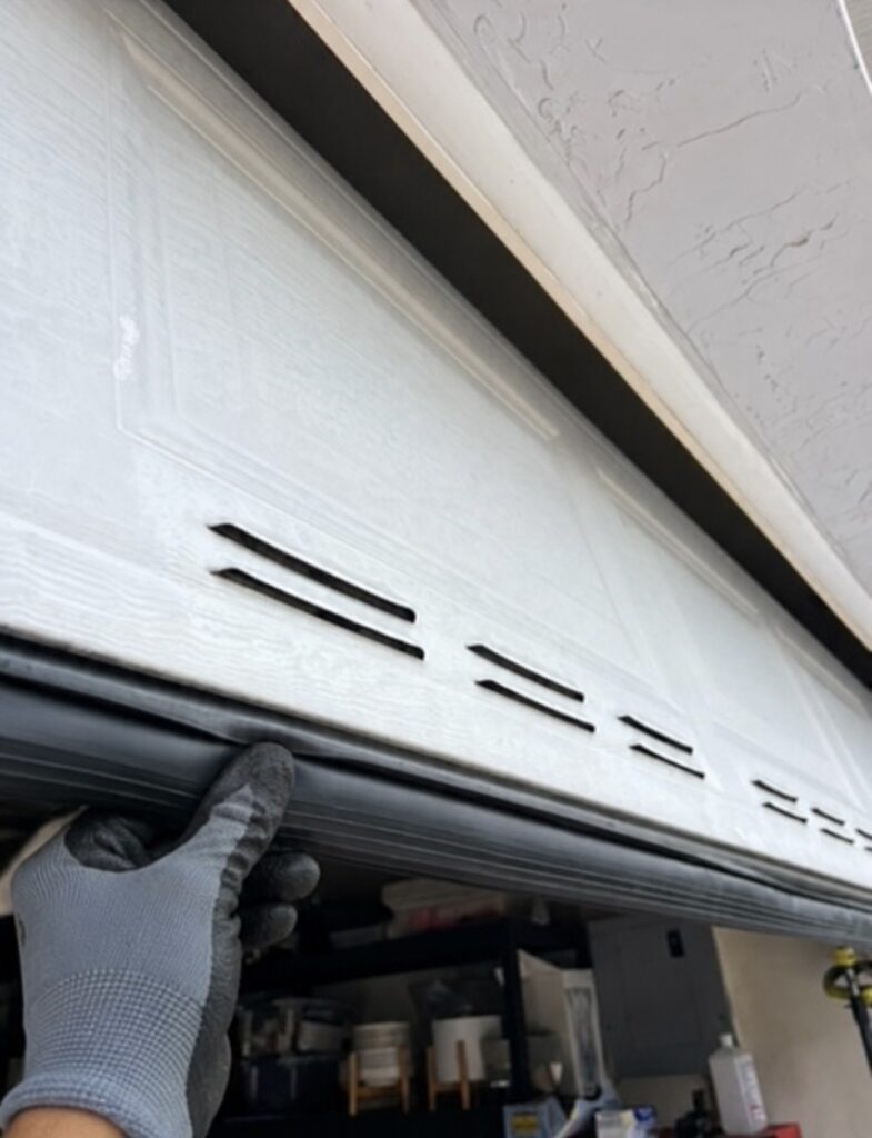 Technician installing a new garage door bottom seal during a weather seal replacement service in Chicago’s North Shore, Illinois.