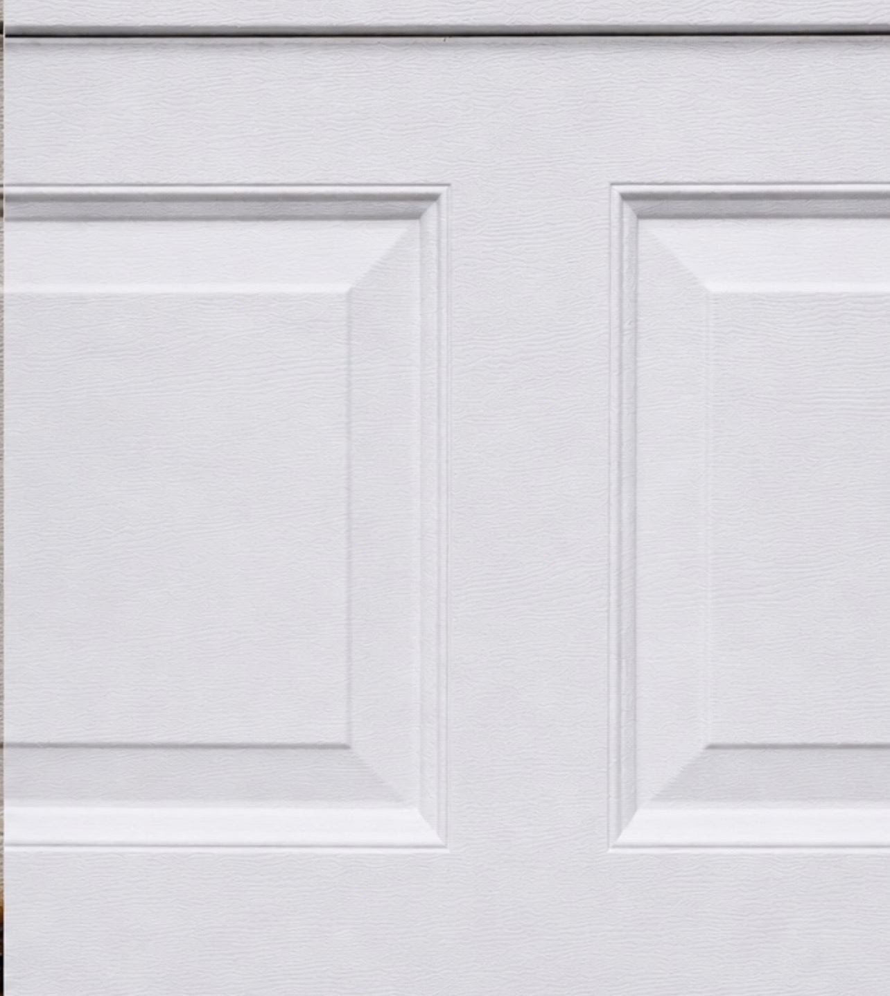 Close-up of a white insulated garage door panel with raised trim detail