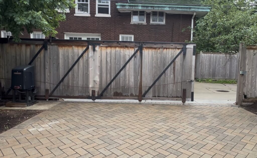 Automatic sliding driveway gate with visible motor operator, shown nearly closed