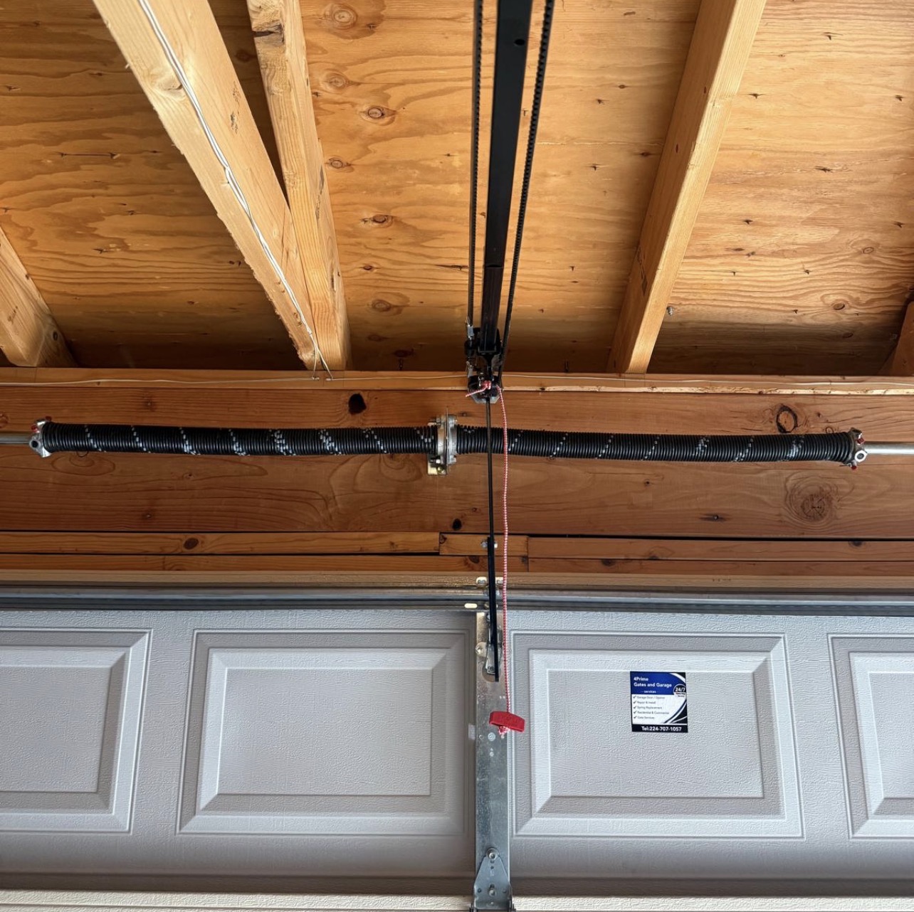 Garage door torsion spring mounted above a residential garage door serviced by 4Prime Gates and Garage