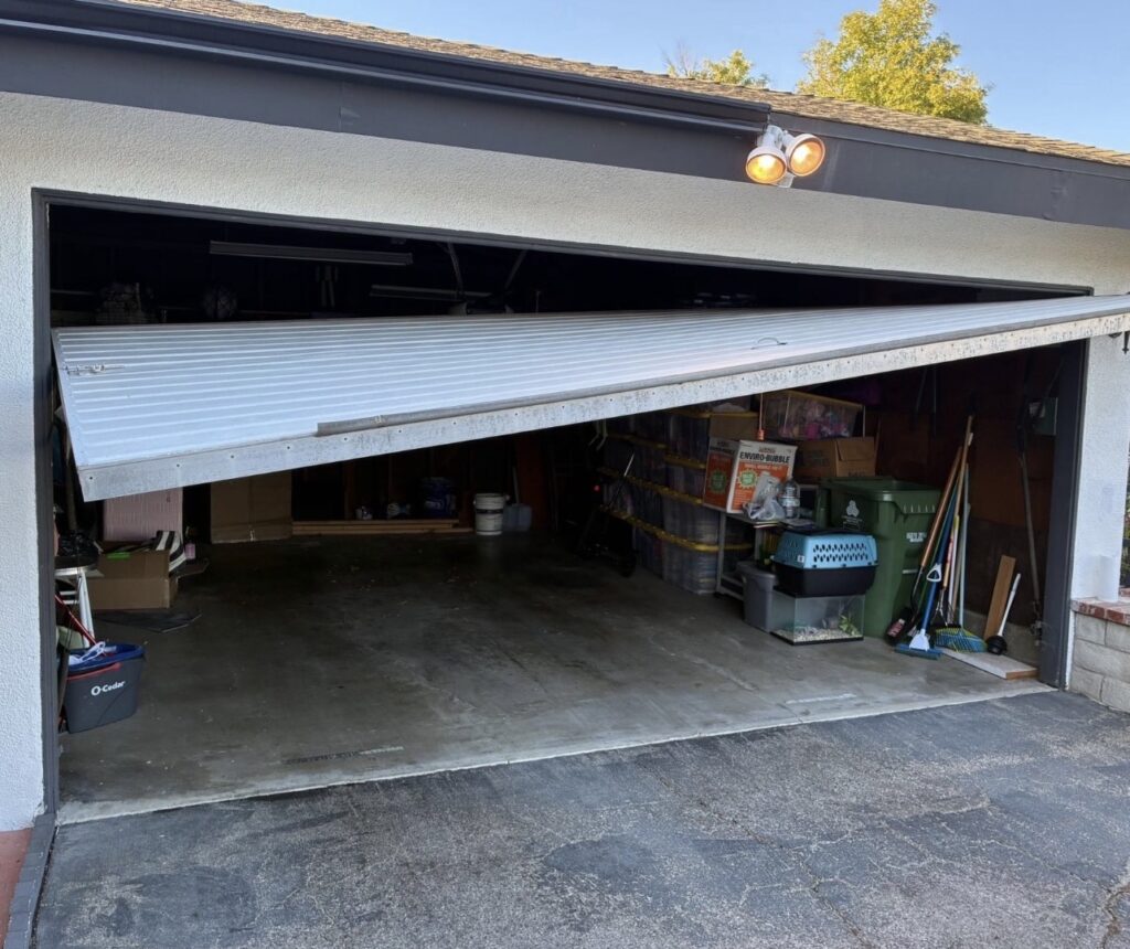 Garage door off its track, showing storm-related damage to a residential garage