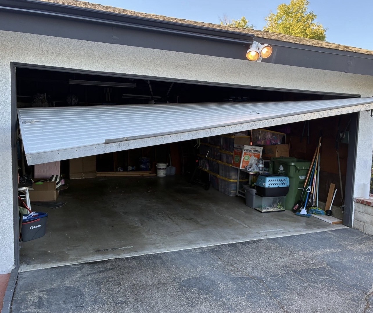 Garage door off its track, showing storm-related damage to a residential garage