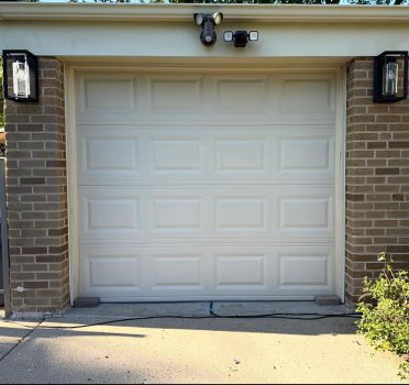 White raised panel garage door installed on residential home with exterior light fixture, Chicago suburbs